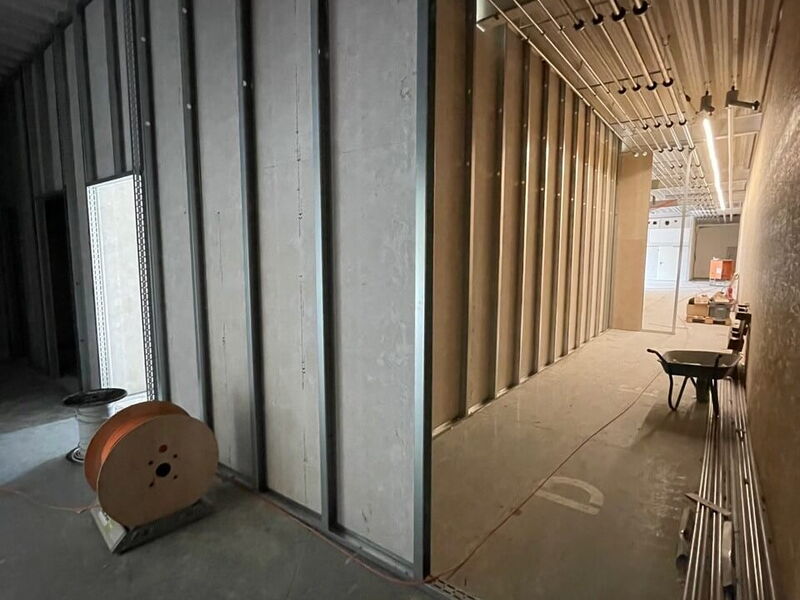 Baustelle mit Metallgerüst und Kabeltrommel, im Hintergrund eine Schubkarre und Rohre